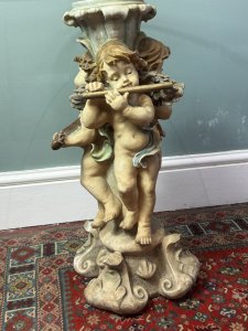 Trio of musical cherubs occasional table Composition - Resin and glass Circa - Vintage Listing Description Ornate table base comprised of entwined cherub figures each holding a different musical instrument (loot, harp, and flute) A richly coloured three dimensional piece with circular glass top. Dimensions in Cms Height 61cm X Top Width 50cm X Base Width 28cm
