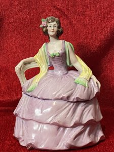 A Fashionable Elaborate Three Tiered Crinoline Gown With Bustier Bodice Decorated With Central Green Bow And Vibrant Yellow Scarf Placed Over Arms. Charming Details With Small Pointed Shoe Poking Out From Under The Gown.
