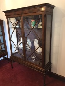 Tall Antique Georgian Chippendale Style Display Cabinet With Chamfered Legs Two Astroglazed Doors With Diamond Shaped Pains With Two Glass Shelves With Delicate Purple Fabric Interior. Beautiful Hand Crafted Cabinet In Solid Mahogany Sits Upon Stunning Tall Chamfered Legs Elegant And Useful For Display Of Fine China And Trinkets With Original Key Condition- Stunning Antique Dimensions In Inches Height 72” Width 53” Depth 16”