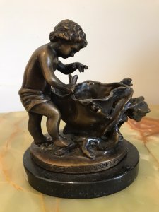Fine Reproduction French Bronze Cherub With Flora Urn Statue. Bronze Putti In Fine Detail Holding Flower Beside A Floral Urn Decorated With Forna Vines On A Oval Black Marble Base Exceptionally Ornate With Stunning Patina Composition- Bronze Dimensions Height 6 3/4” Width 5.5” Depth 4.5” Weight 3kg Approx