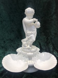 Putti Standing On Pile Of Books With A Globe In Hand, In The Form Of A Water Fountain. Masked Heads In Oyster Shell Shaped Trio Of Dishes For Fruits/ BonBons Or Canapés. Table Centre Piece Fruit Comport/ Statue.
