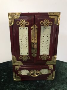 Vintage Oriental Brass Bound Jade Panelled Jewellrey Casket Beautiful Casket With Two Doors Revealing Three Internal Shelves And Opening Bottom Drawer Front And Two Side Panels Have Fine Shaped Jade Carved Insets With Ornate Brass Engraving Ornate Brass Carry Handle On The Top Shaped Feet Very Ornate Unusual Casket Perfect For Jewels, Documents Or Trinkets Made From Hardwood With Quality Workmanship Circa - 1950’s Origin - China Dimensions In Inches Height 11” Width 7 1/4” Depth 5.5” Weight Approx 10kg
